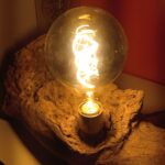 Lampe unique sur socle en bois flotté avec une ampoule Edison sur un meuble moderne allumée vue ampoule