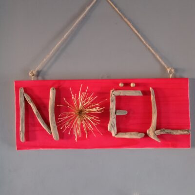 Pancarte festive rouge avec le mot "NOËL" en bois flotté et une étoile dorée, suspendue par une corde.