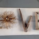 Pancarte en bois avec le mot "LOVE" formé de bois flotté et d'une fleur sèche, suspendue par une corde de jute.